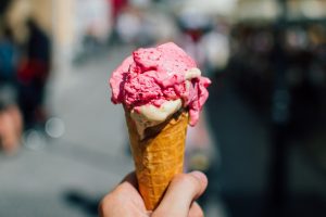 Person Holding Ice Cream Cone with Scoop of Pink Ice Cream